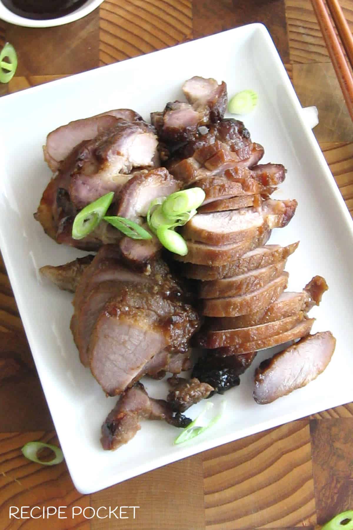Slices of barbeque pork on a white plate.