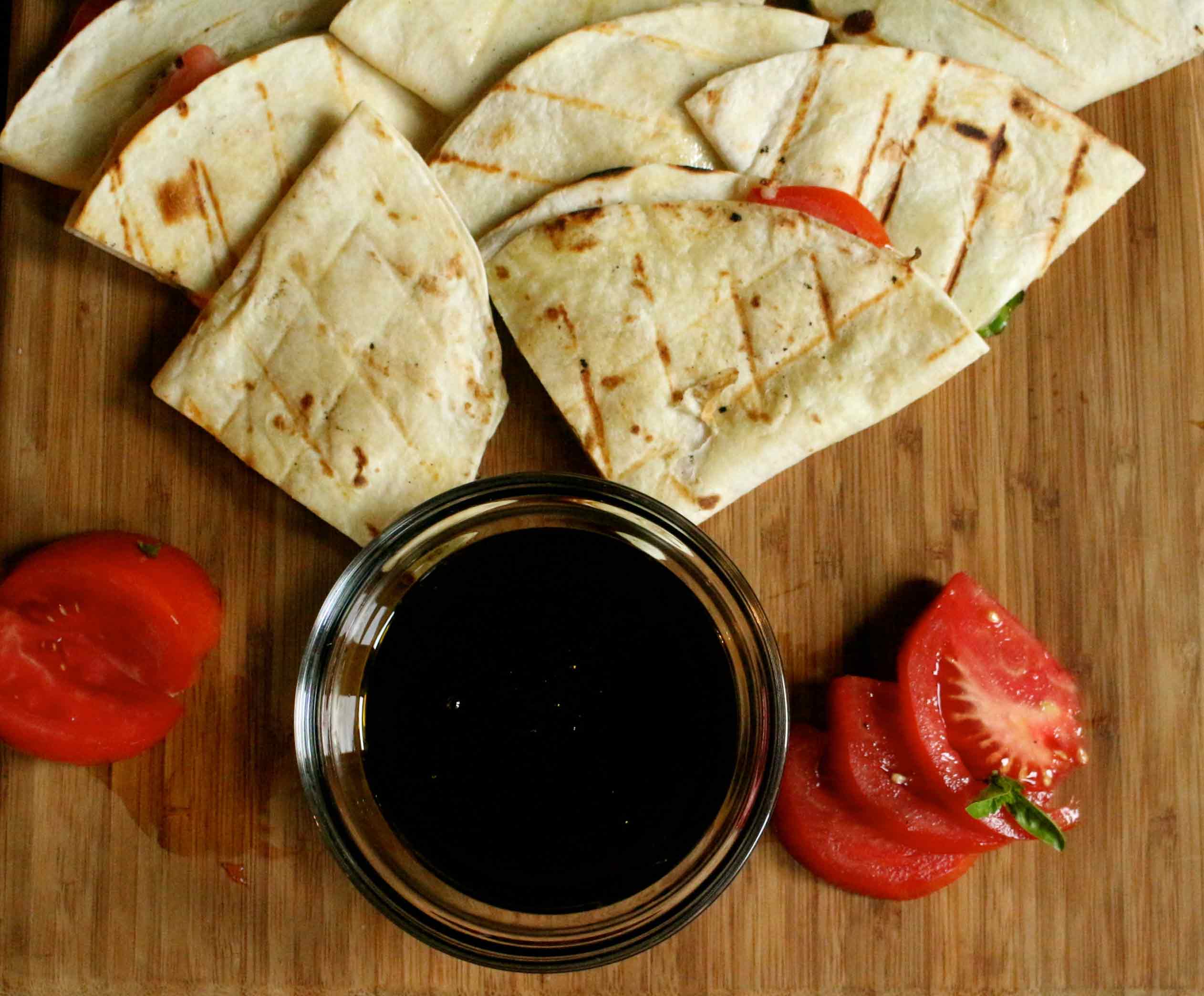 Tomato and cheese quesadilla on a brown board.