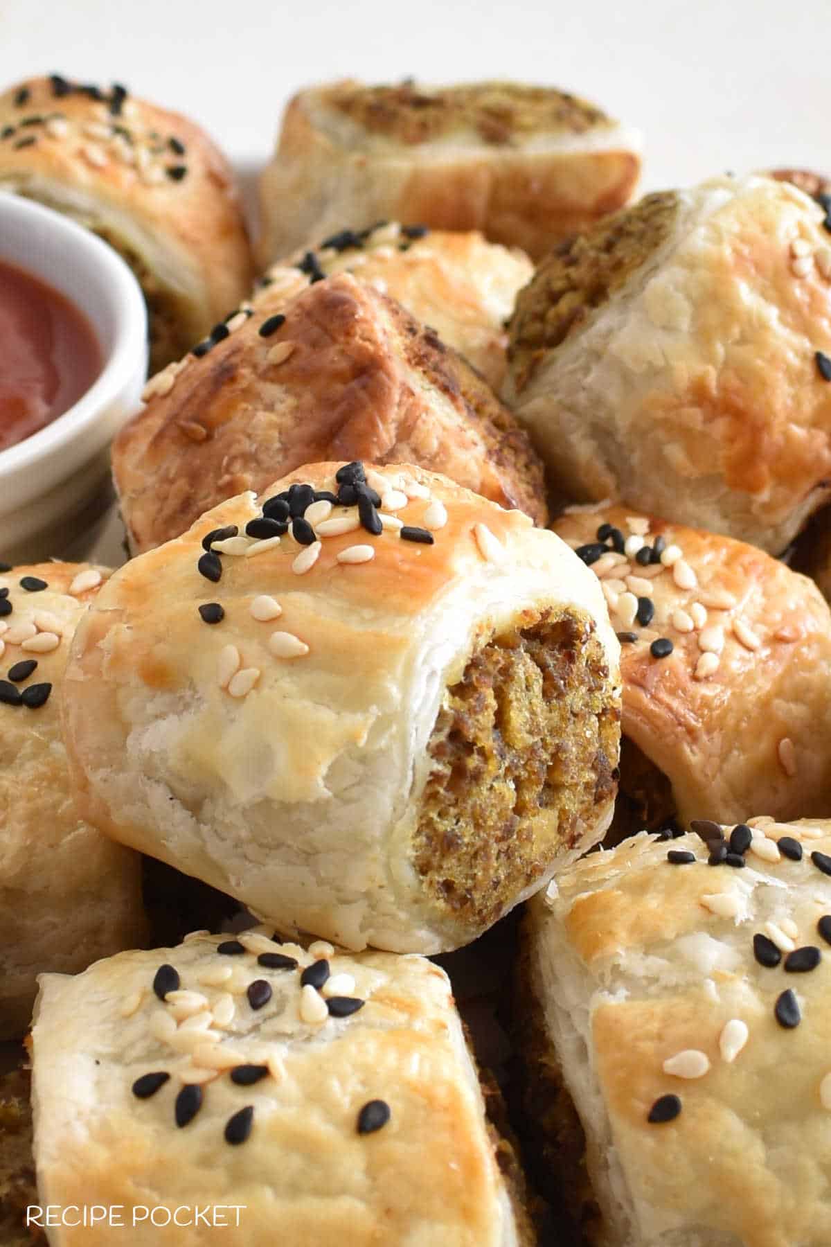 Closeup of beef puff pastry rolls showing sesame seeds on top.