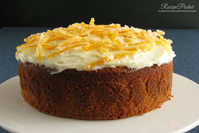 Cream cheese frosting and crystallized orange peel decorations on an orange juice cake made from scratch.