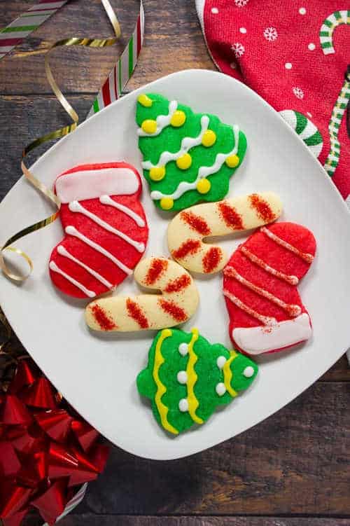 Christmas stockings and mittens cookies on a square white plate.