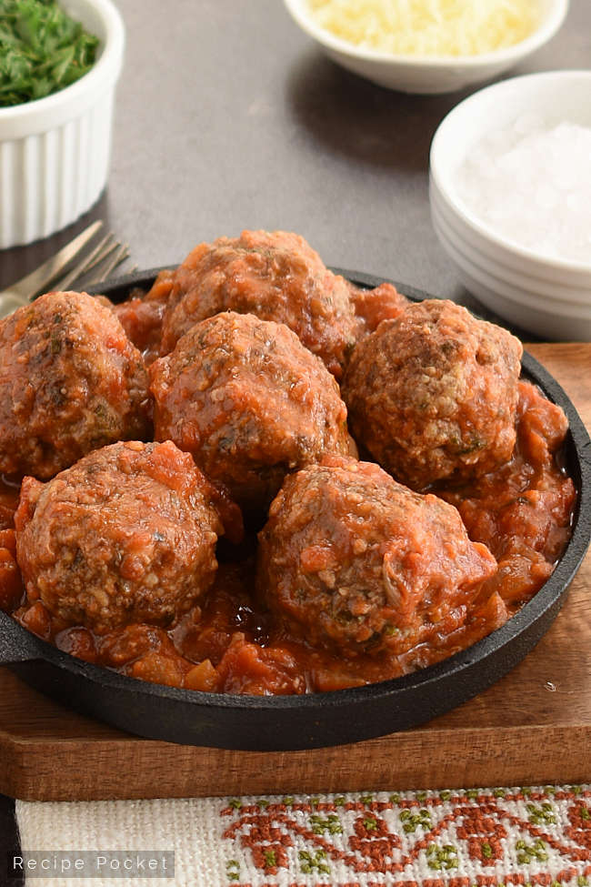 Slow cooker meatballs in tomato sauce served in a cast iron pan.