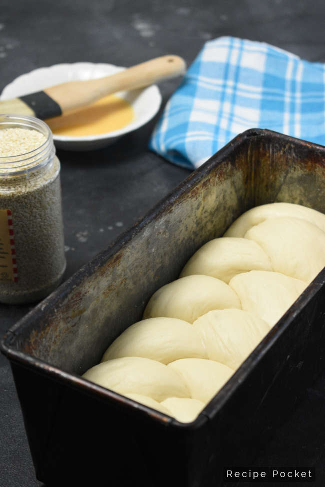 Image of braided bread dough in baking tin.