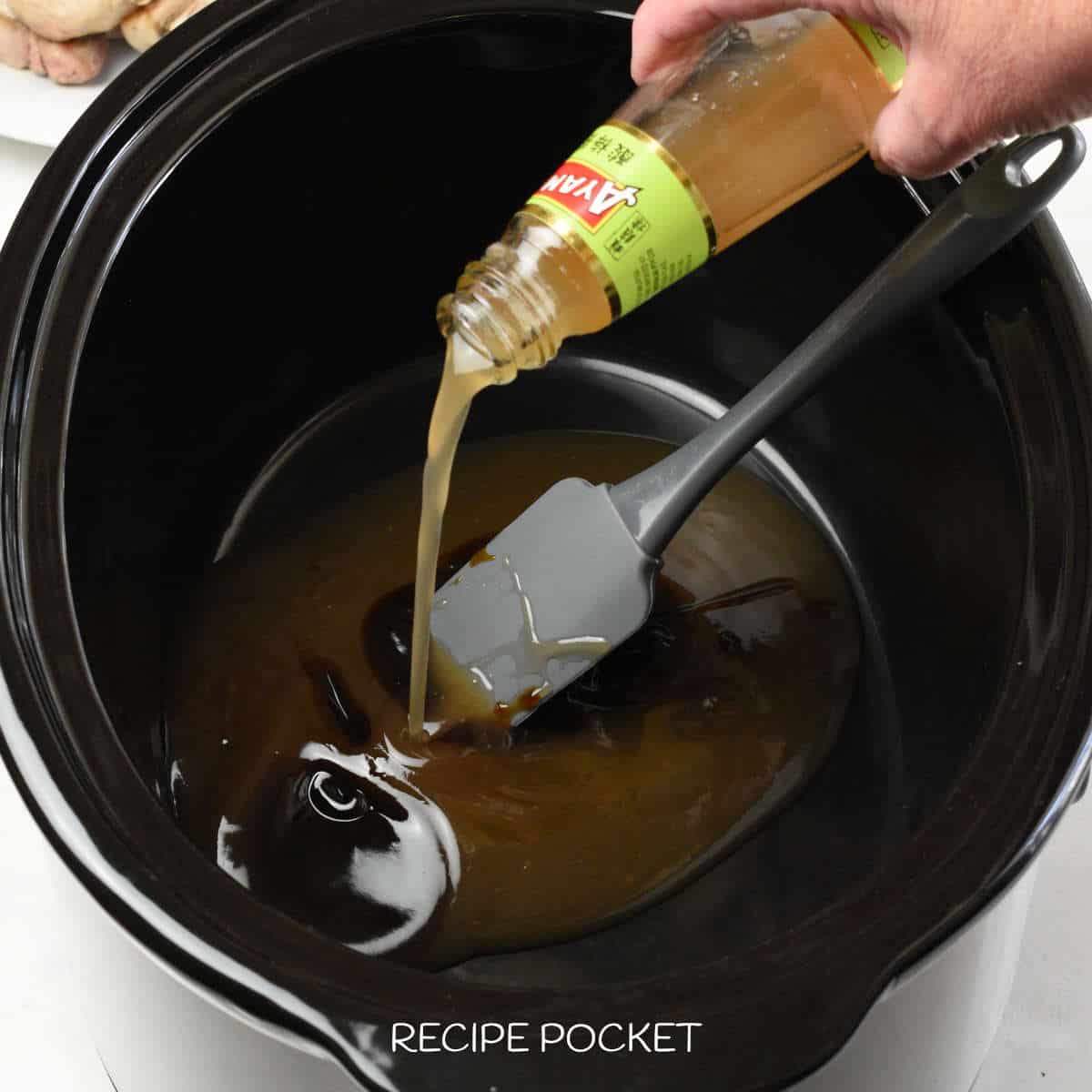 Sauce being poured into a slow cooker.