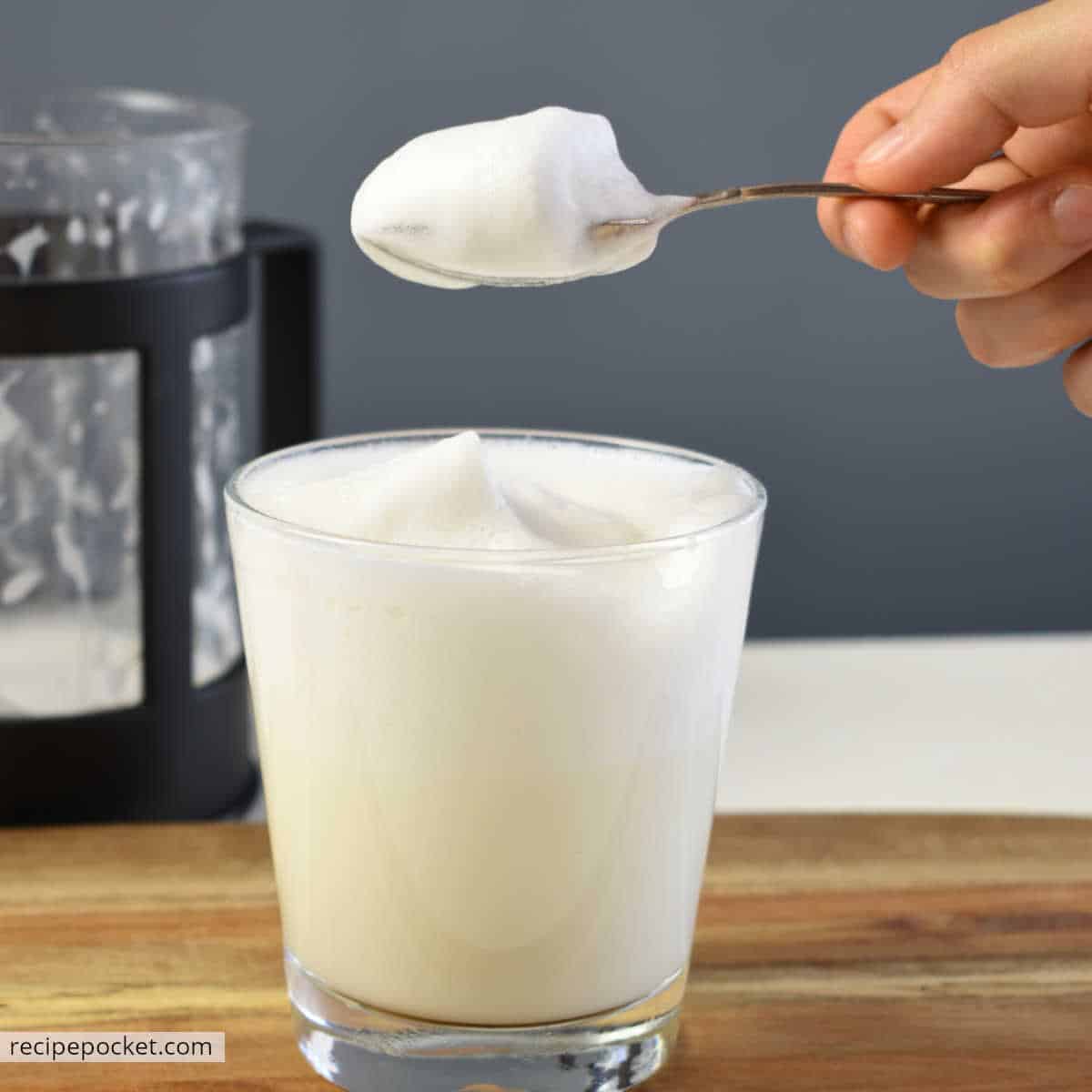 Milk froth in a glass and on a spoon.