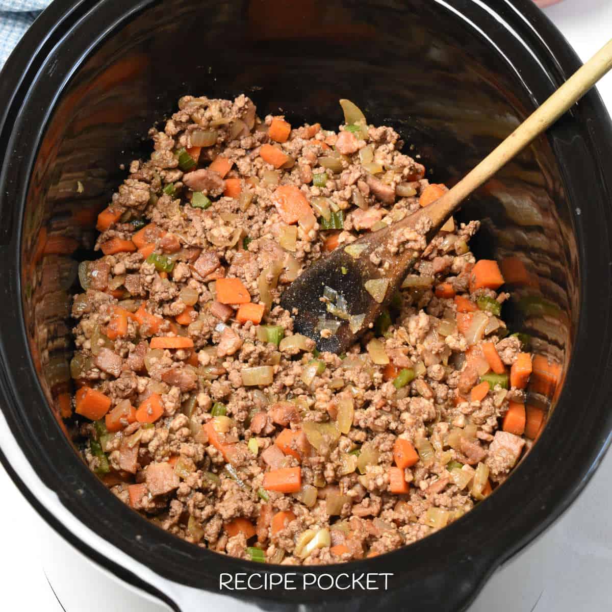 Meat and vegetables in a slow cooker bowl.