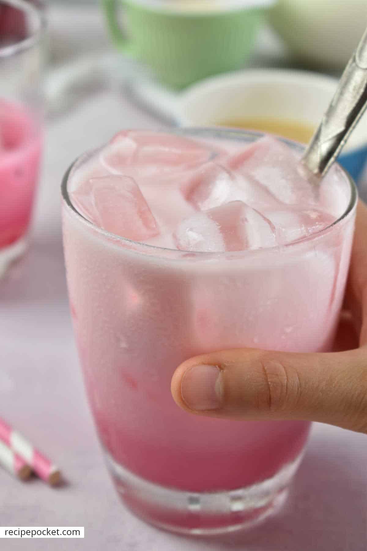 A hand holding a pink drink.