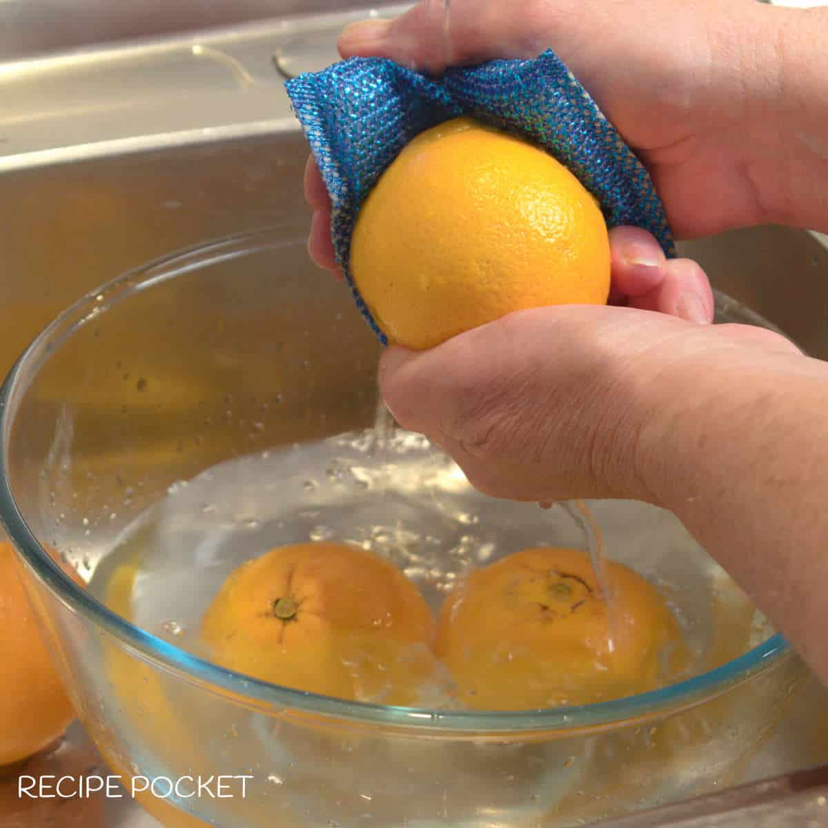 Oranges being washed under running water.