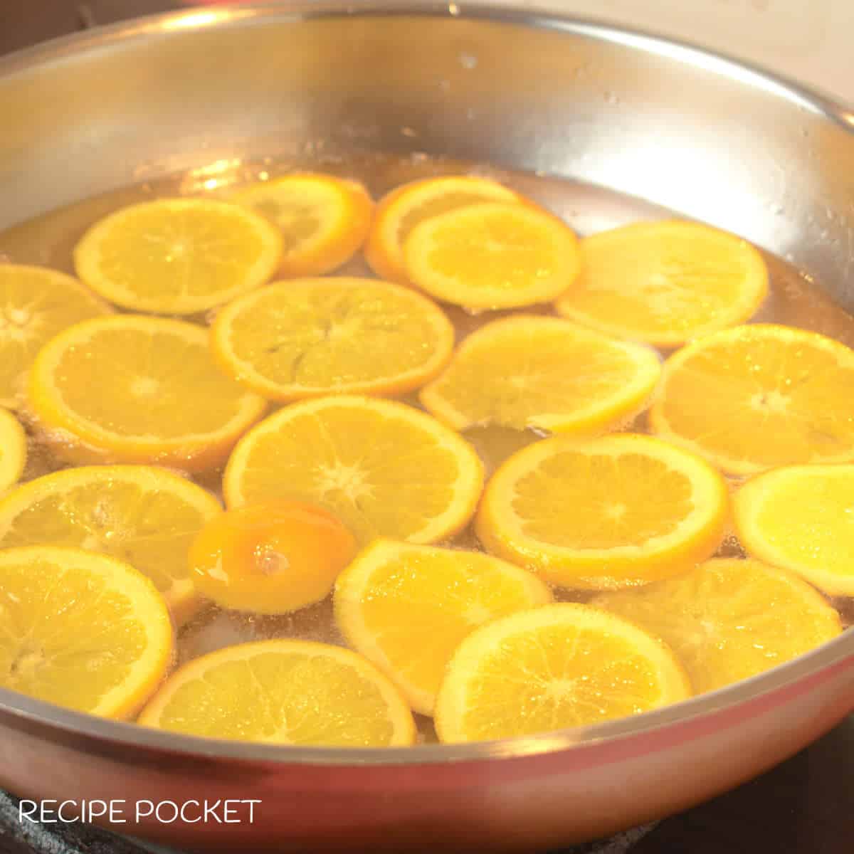 Oranges slices at the start of cooking in sugar syrup.