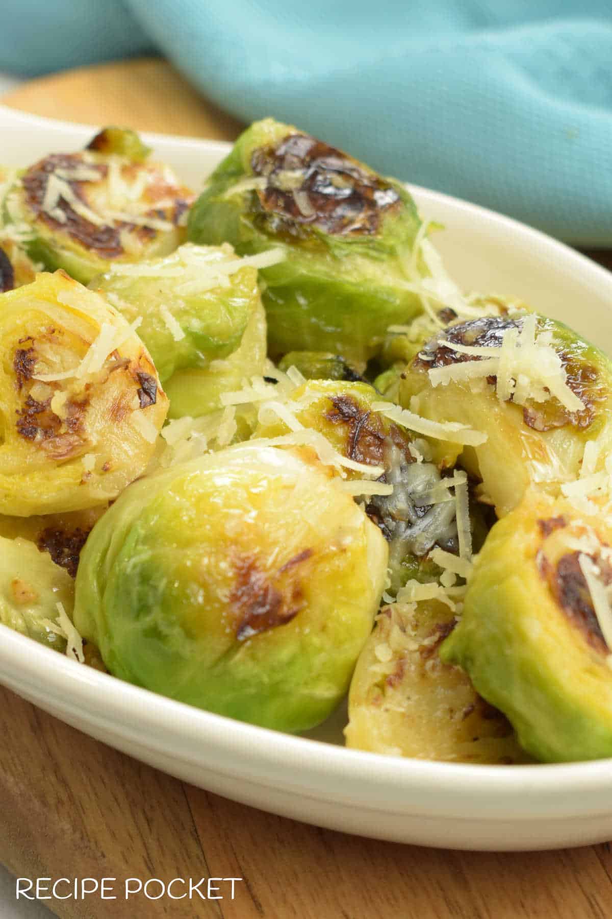 A serving dish the Brussel sprouts on a wooden board.