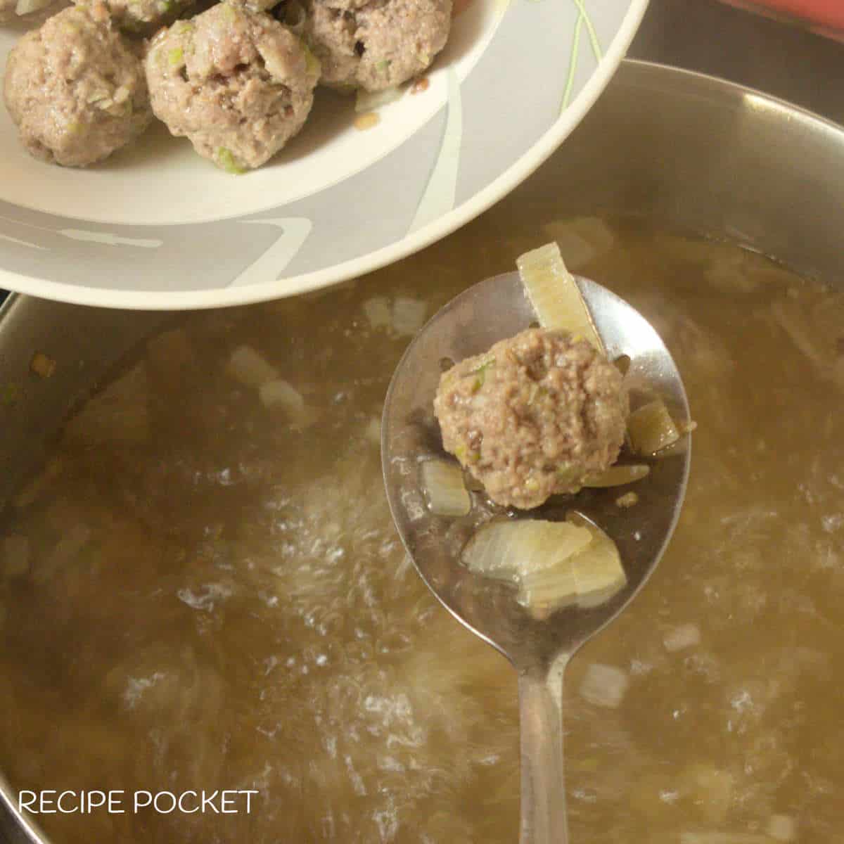 Meatballs being removed from hot soup.