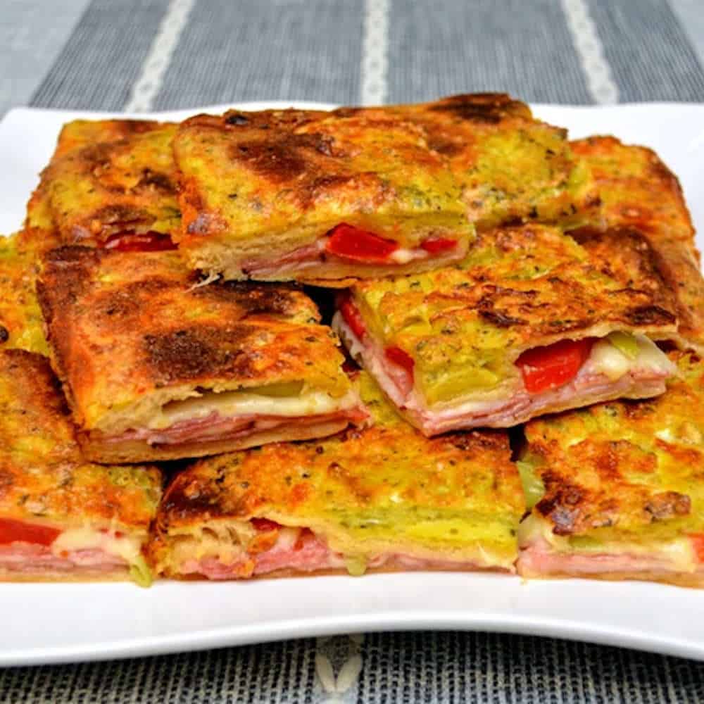Image of a plate of baked antipasto squares.