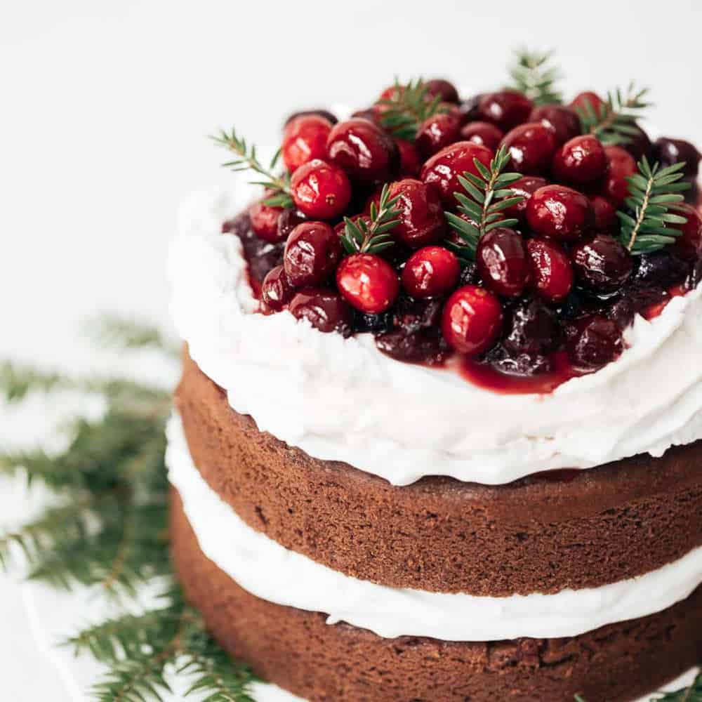 A two layer cake with whipped cram and cranberry decorations