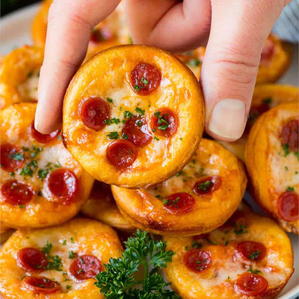 A hand holding a mini pizza.