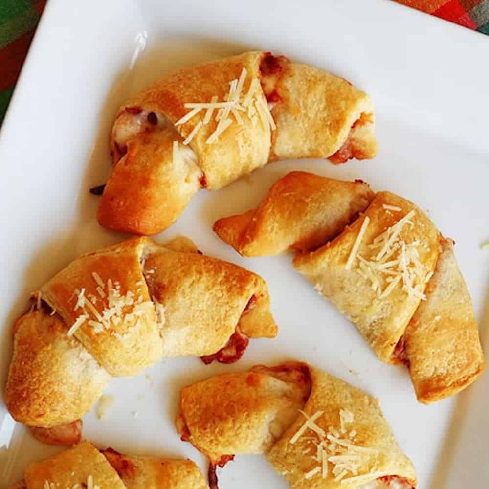 Top down view of pizza crescent roll-up on a white platter.