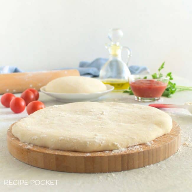 A piece of pizza dough on a board.
