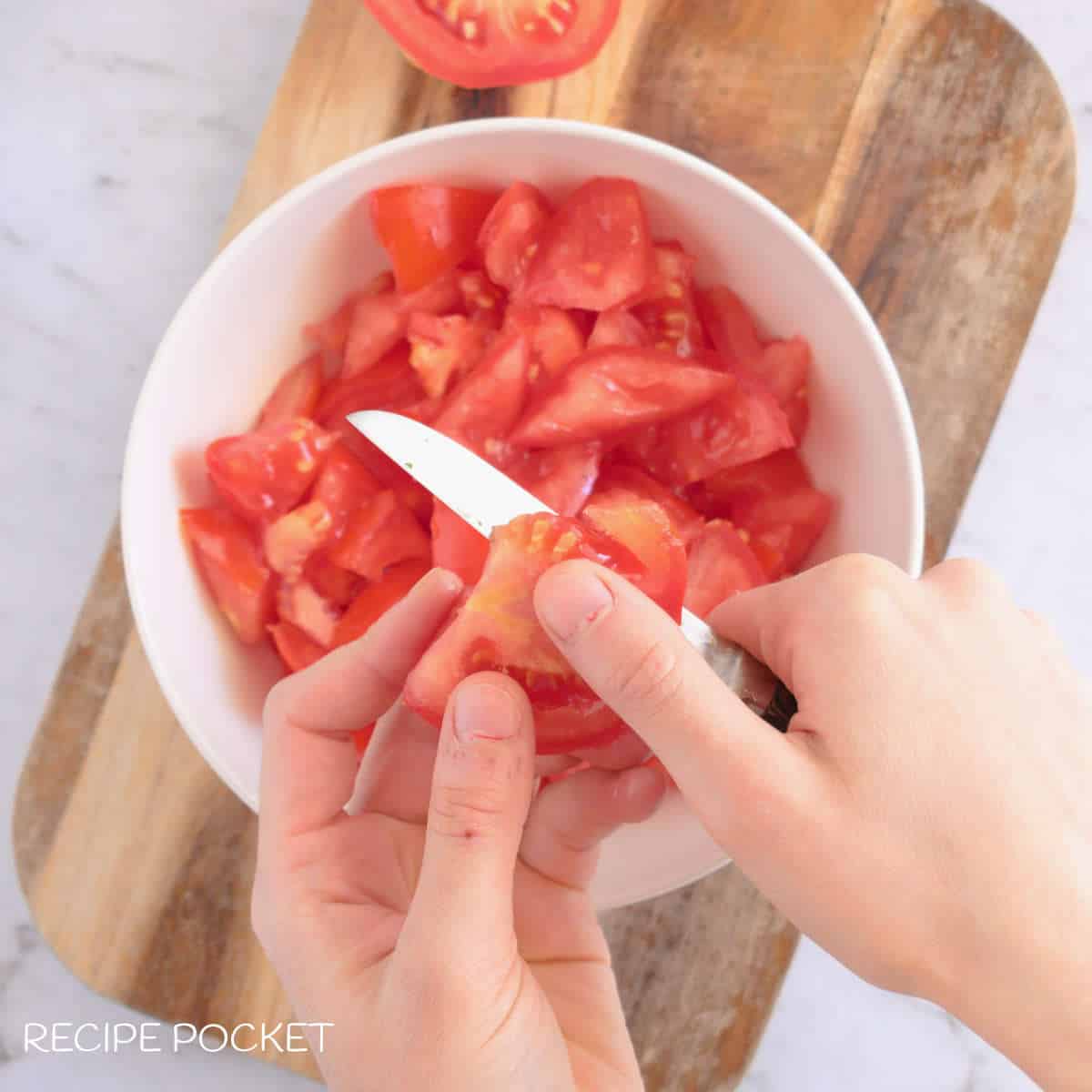 Tomato being cut into small pieces.