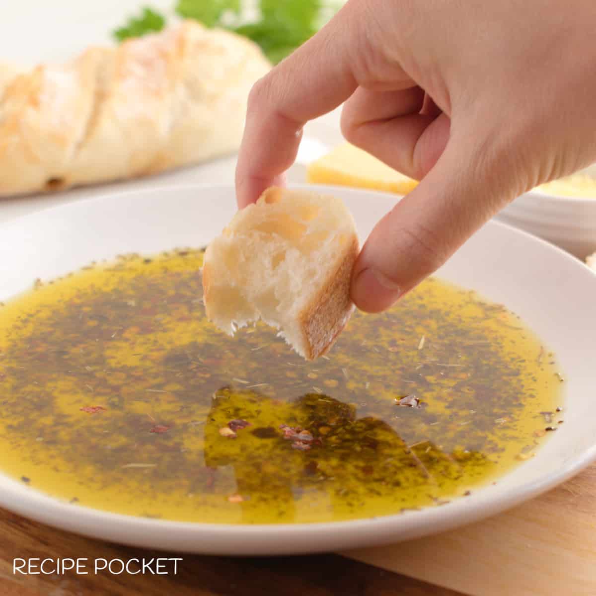 A piece of bread being dipped into flavoured dipping oil.