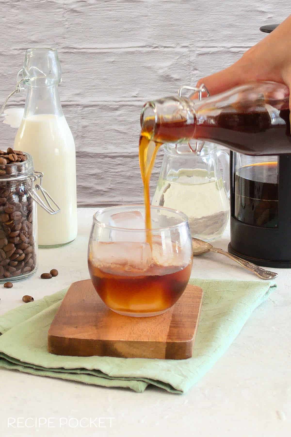 Cold brew coffee being poured over ice in a glass.