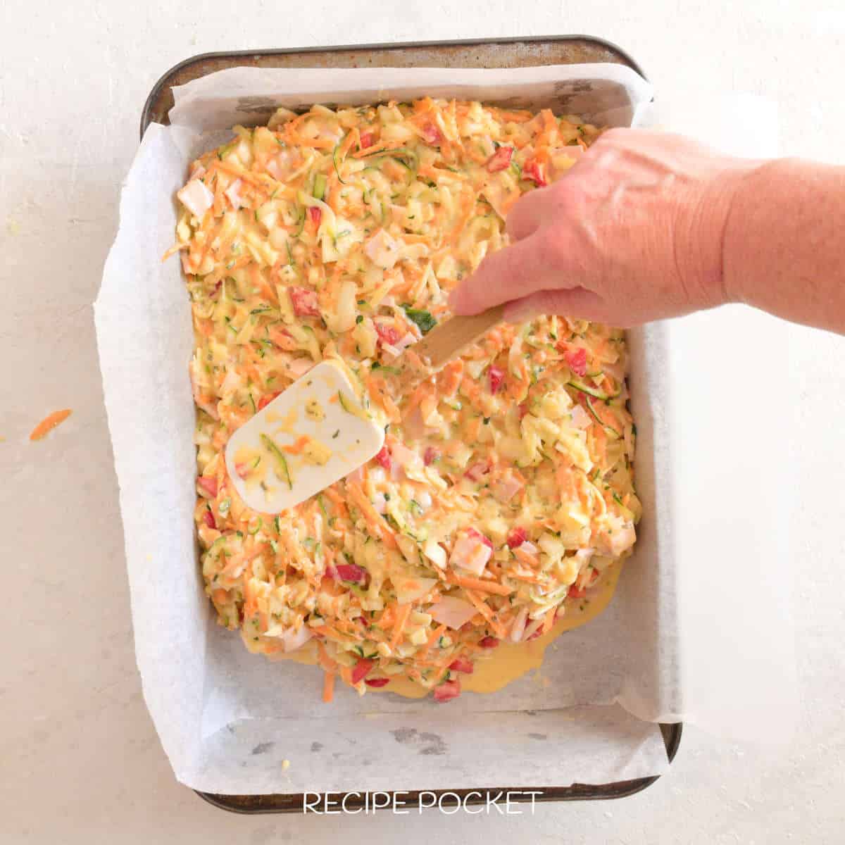 Zucchini slice mixer in a baking tin.