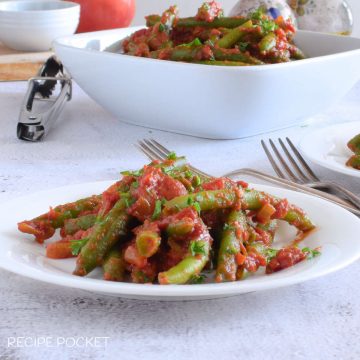 Green beans in tomato sauce on a small plate.