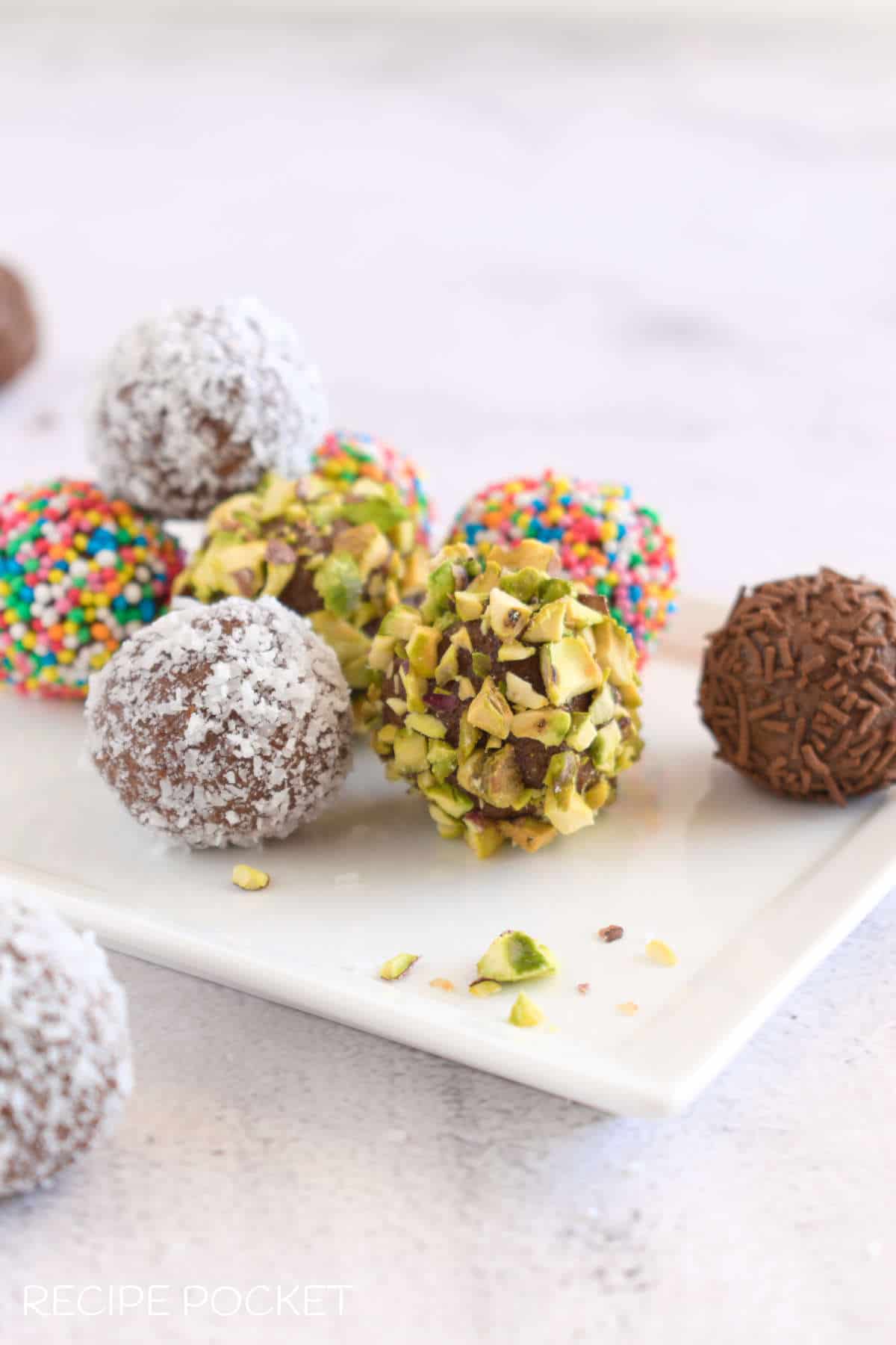 Chocolate truffle balls some coated in chopped pistachio nuts, coconut, chocolate and colored sprinkles. 