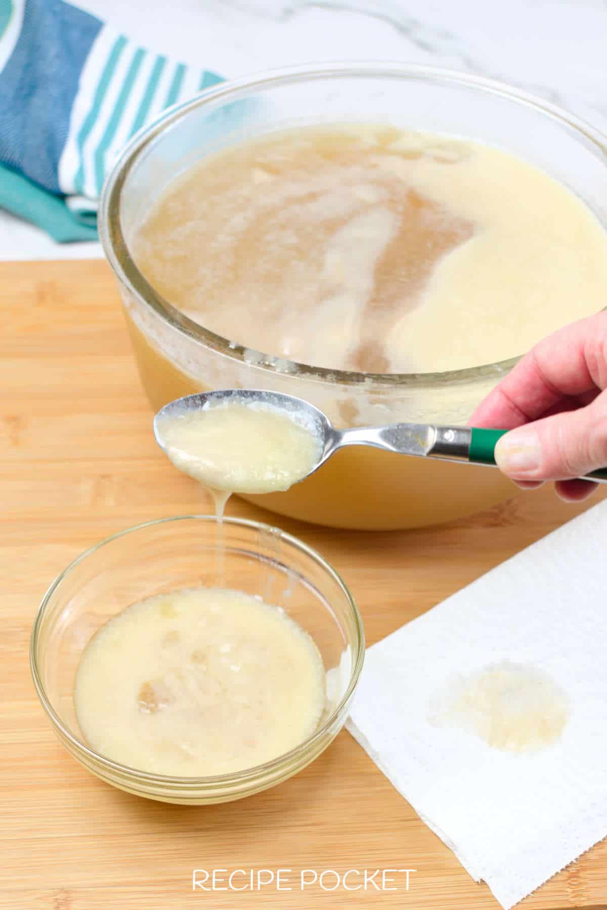 Image showing chicken fat being removed from stock with a spoon.