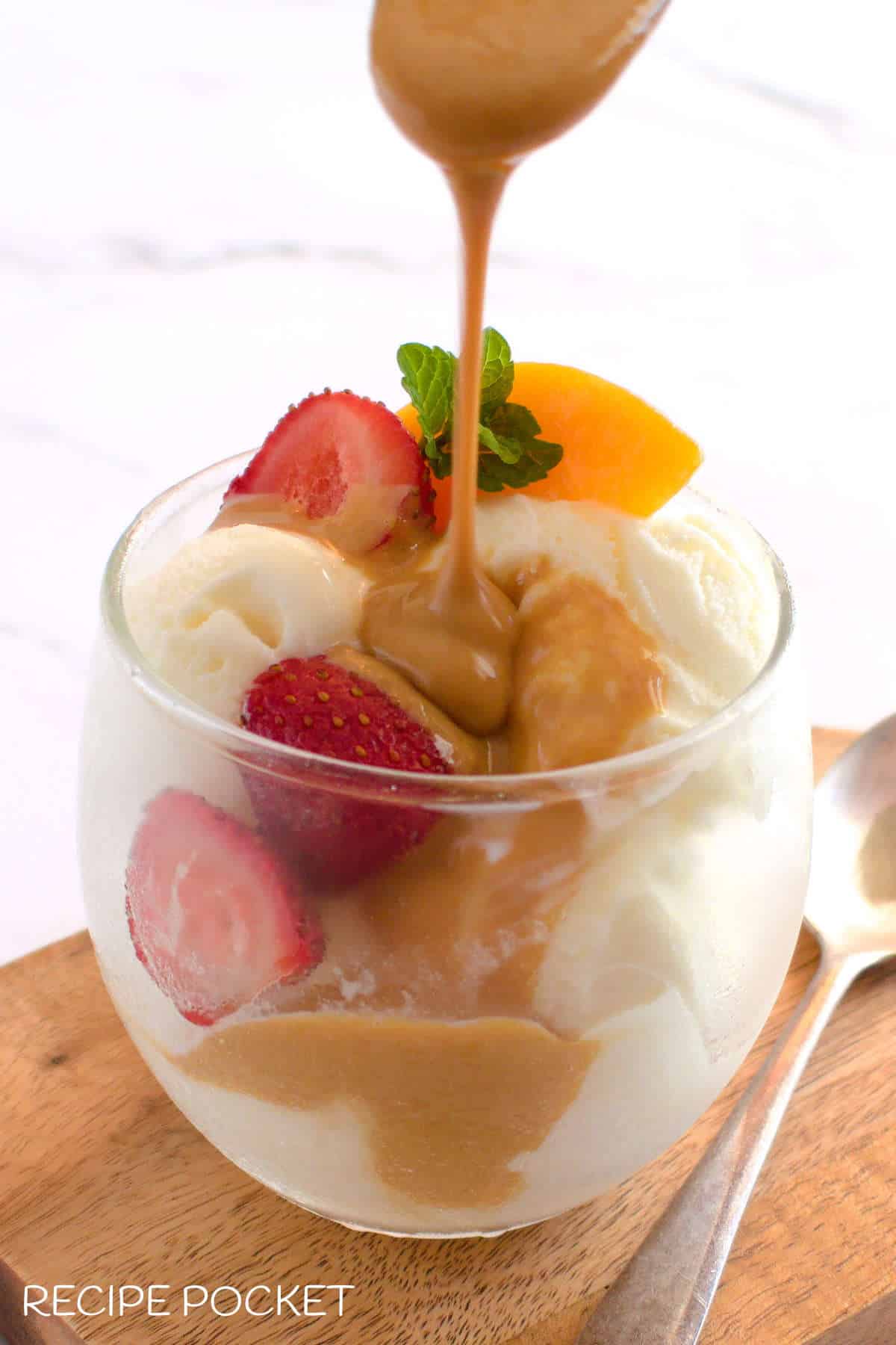 Featured image for article on how to make slow cooker dulce de leche. It show caramel sauce being poured over icecream.