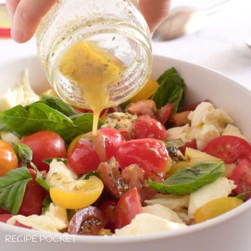 Salad dressing poured onto a tomato basil mozzarella salad.