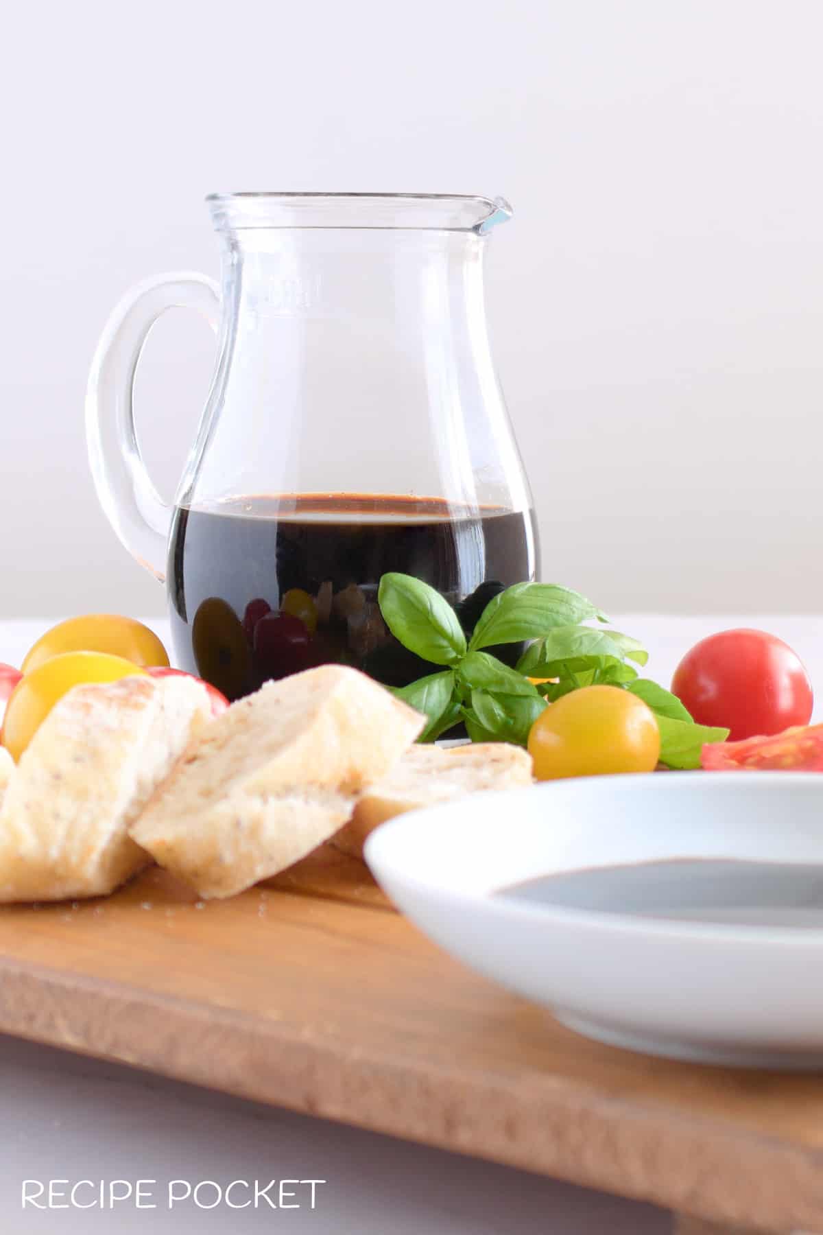 Balsamic vinegar dressing in a jug on a wooden board.