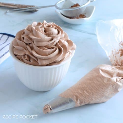 Chocolate flavored cream in a white bowl with a piping bag in the foreground.