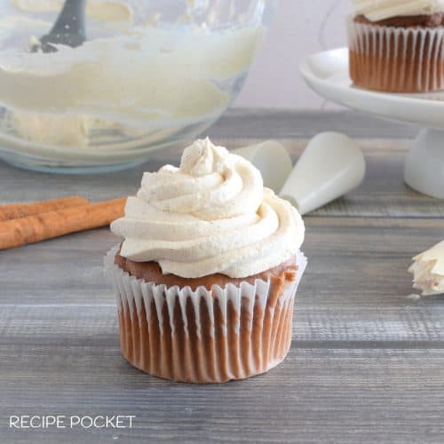 A cupcake with cream on top on a wooden table.