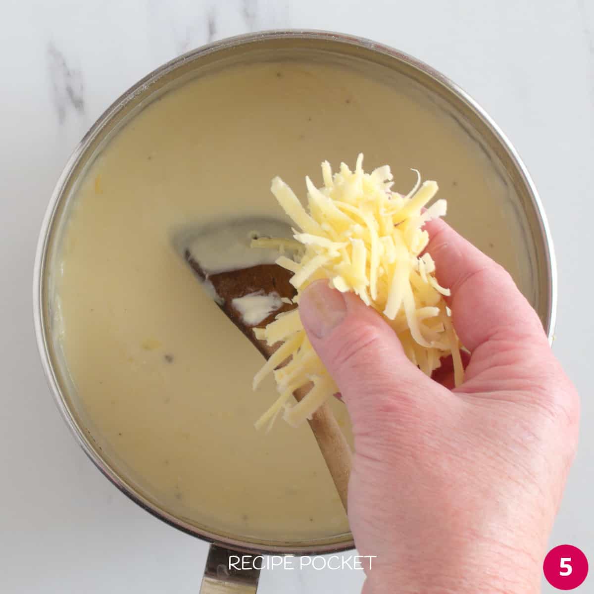 Cheese being added to mac and cheese sauce.