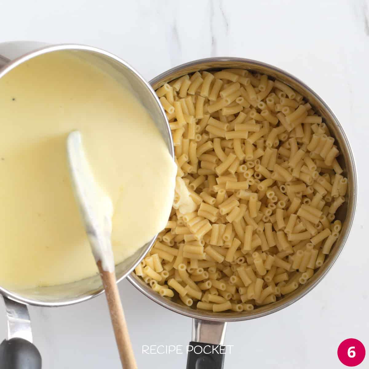 Cheese sauce being poured over cooked pasta.