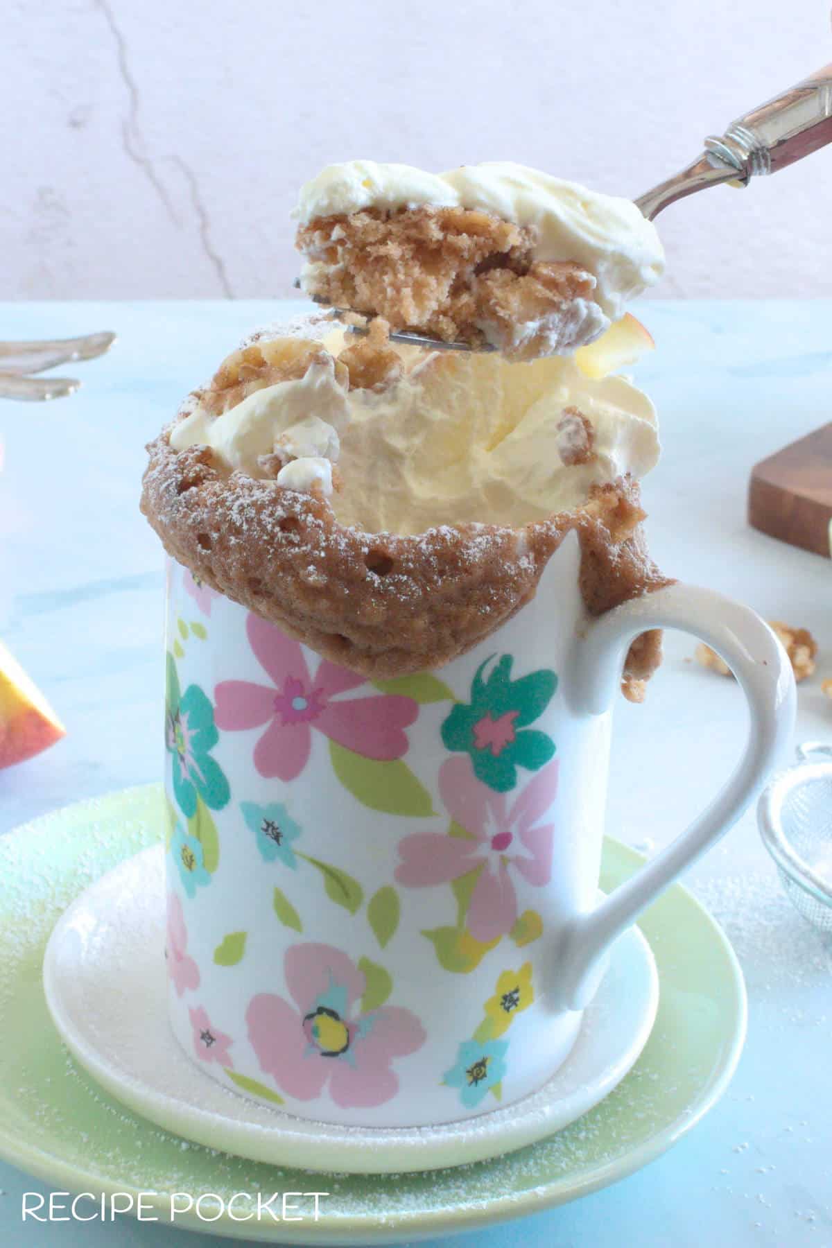 A mug cake being eaten with a fork.