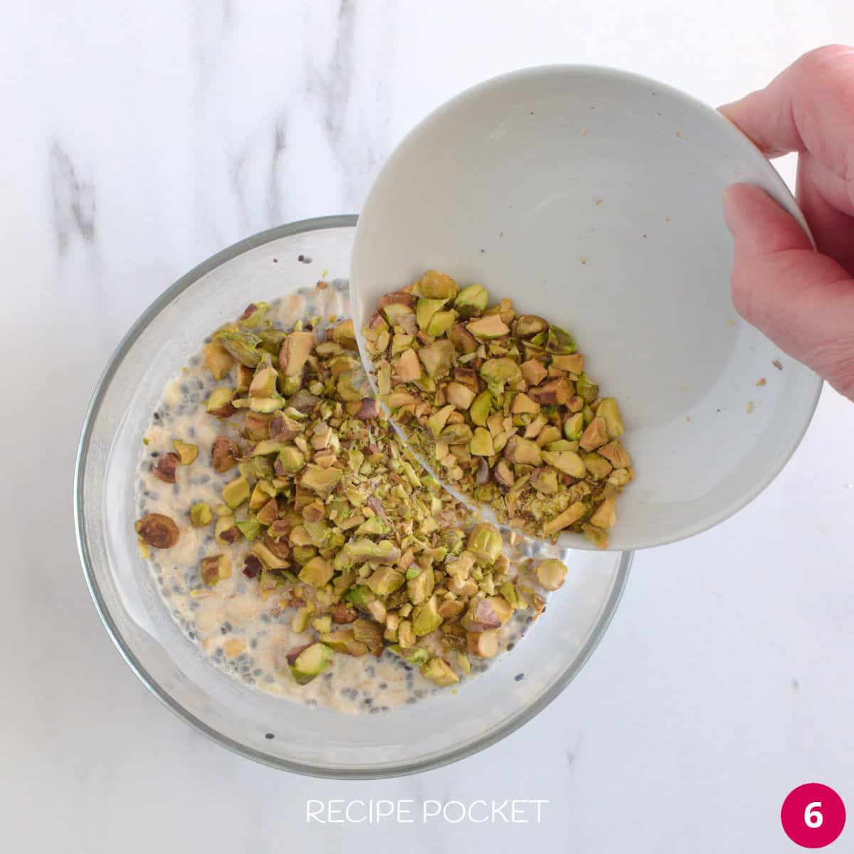 Nuts being added to overnight oats in a bowl.