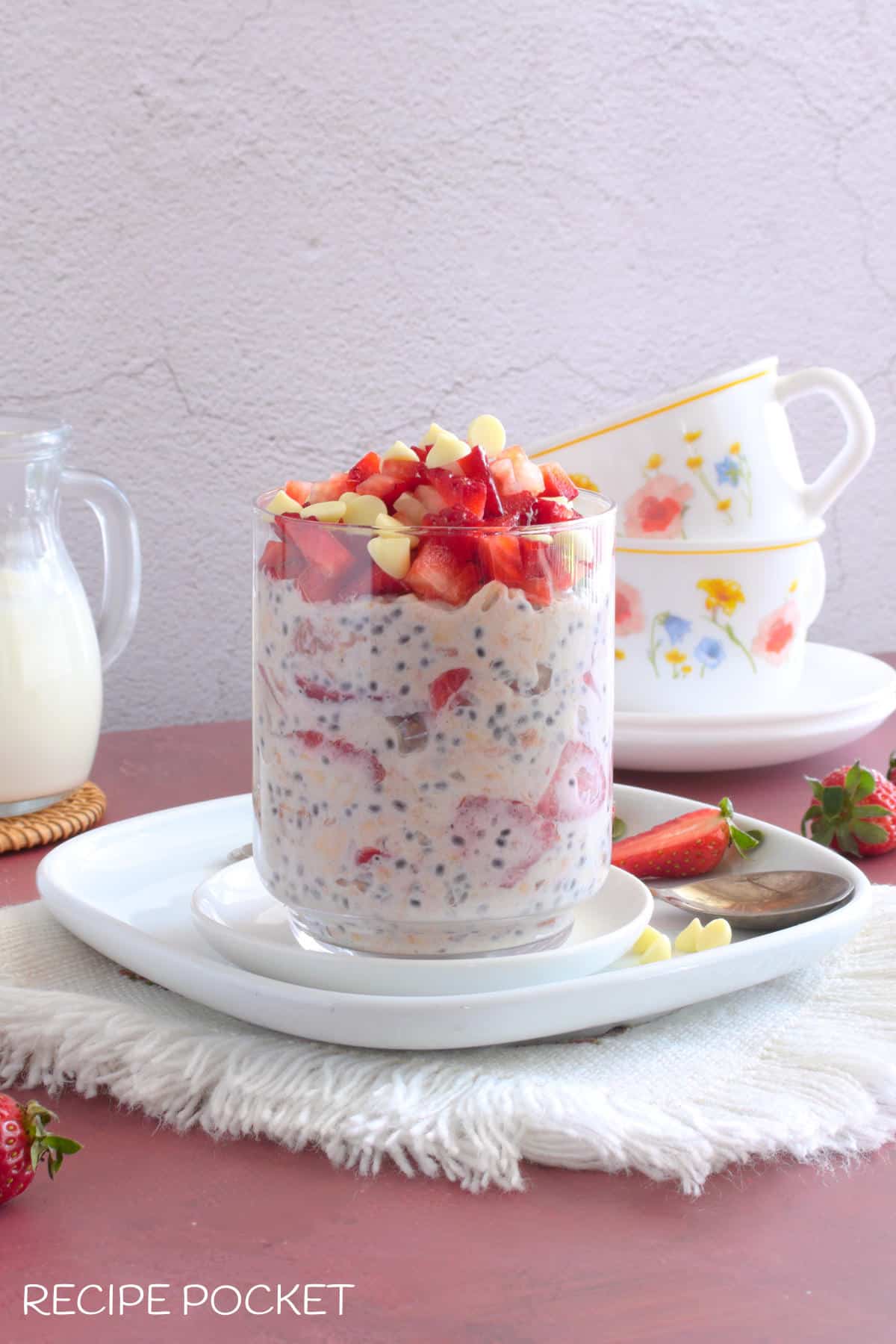 Strawberry overnight oats with two cups in the background.