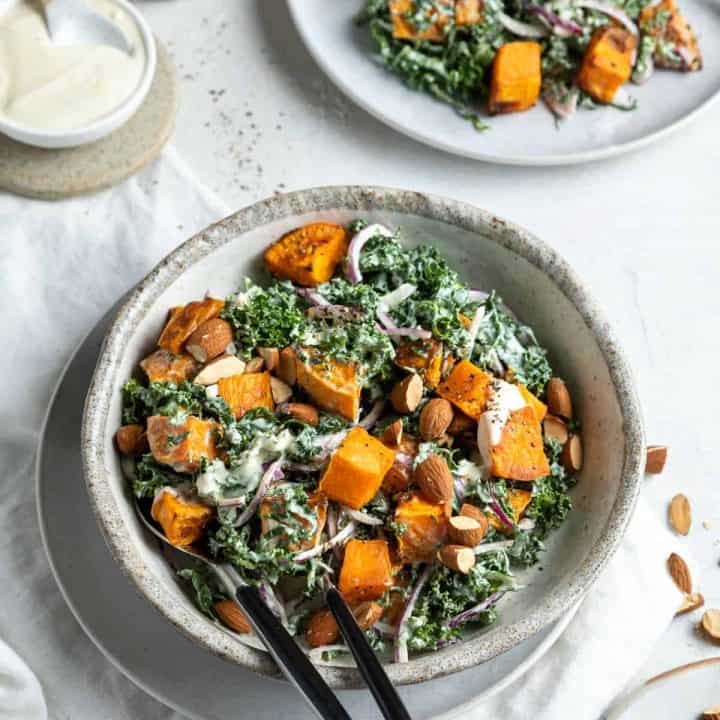 Kale and sweet potato salad in a bowl with serving spoons.