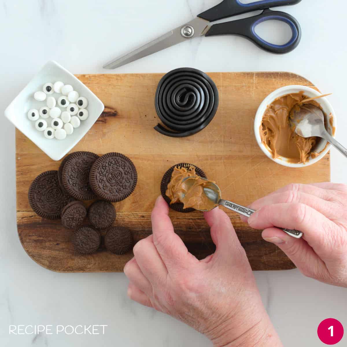 Biscoff spread being applied to the top of an Oreo cookie.