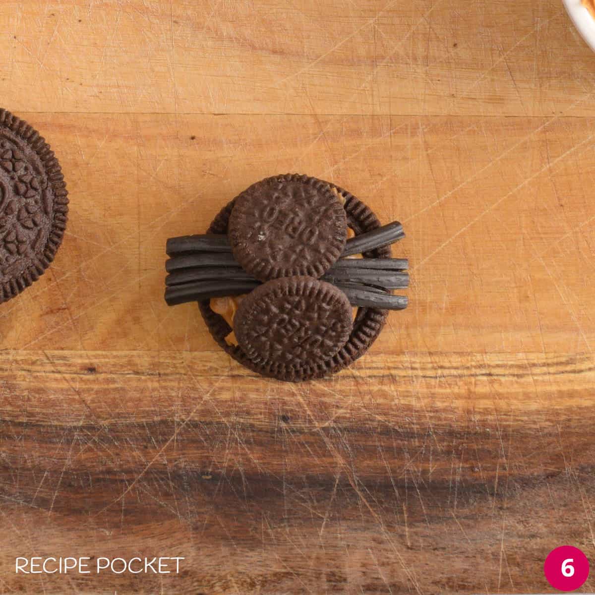 Two halves of mini oreo cookies form a spider body on top of a regular oreo cookie.