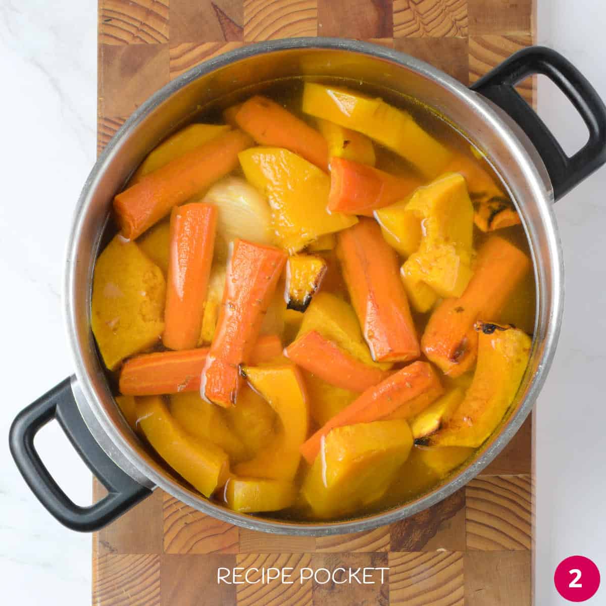 Roasted vegetables in a saucepan with stock.