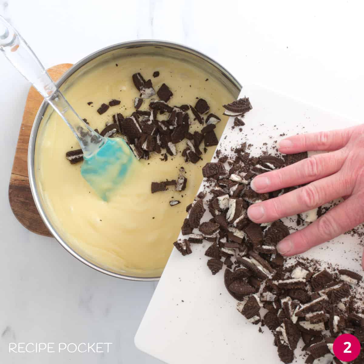 Crushed Oreo cookies being placed into melted chocolate.