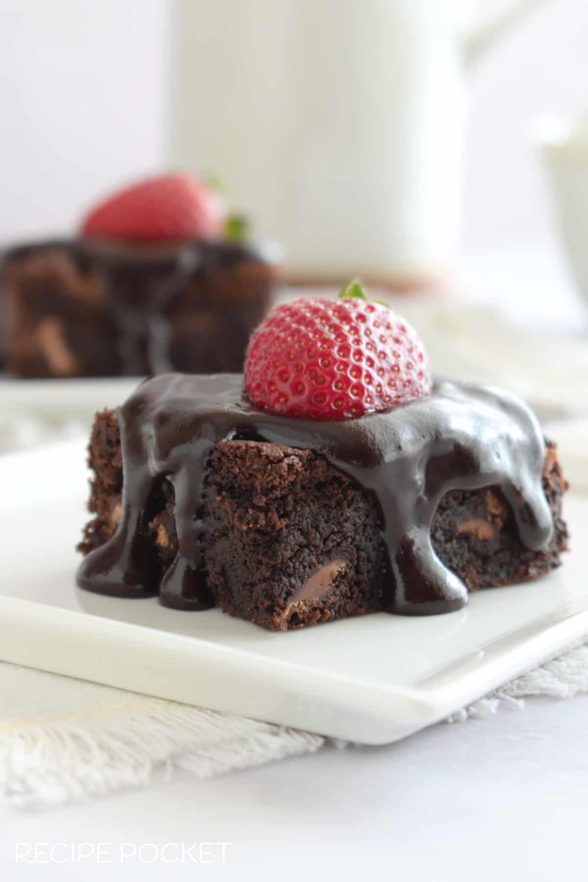 Brownies with a cake mix with a chocolate glaze and a strawberry on top.