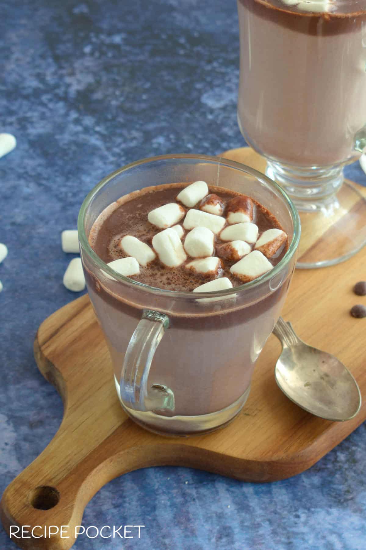 Hot chocolate with marshmallows on a board on a blue table.
