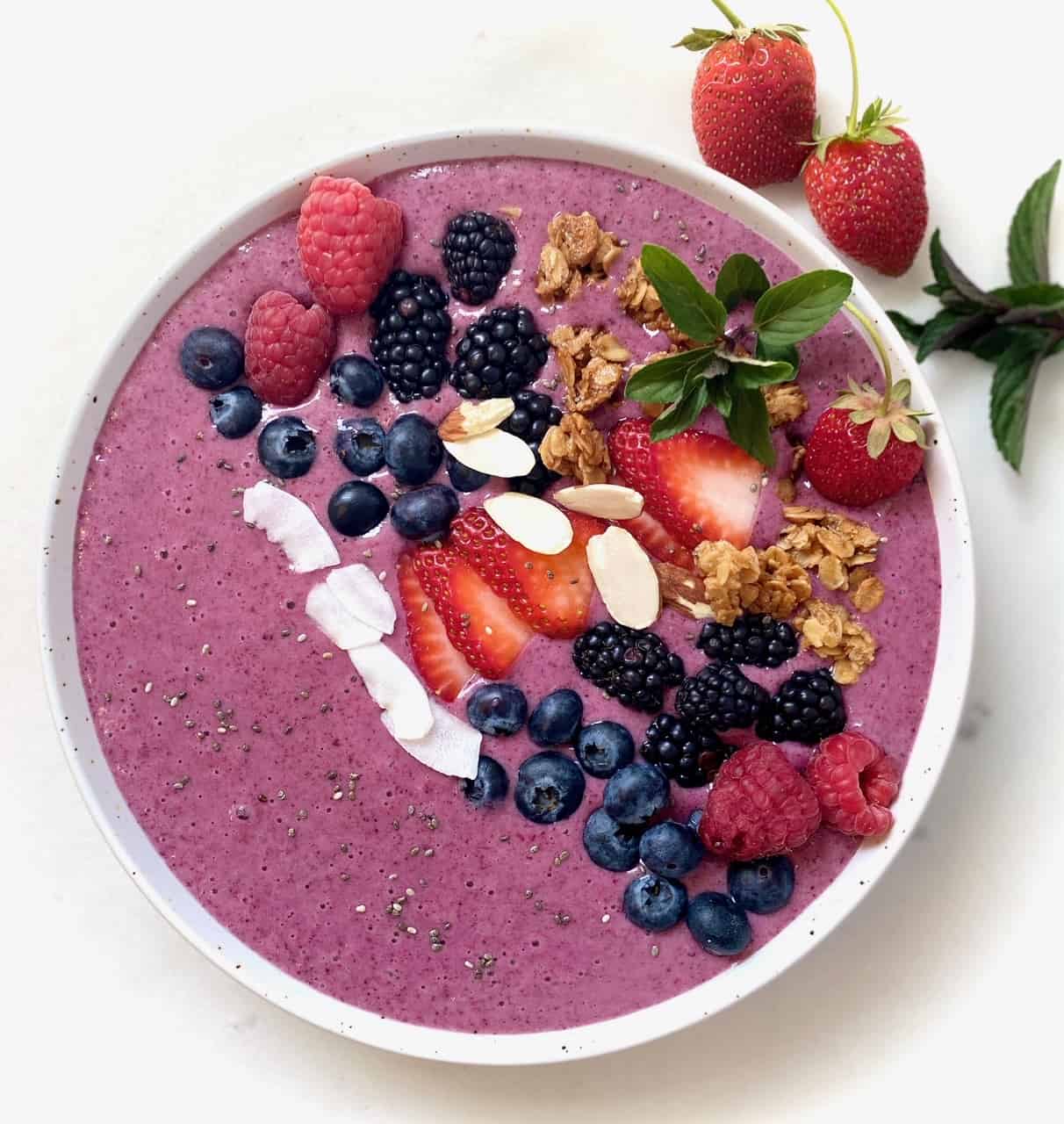 Berry smoothie bowl with fruit on top.