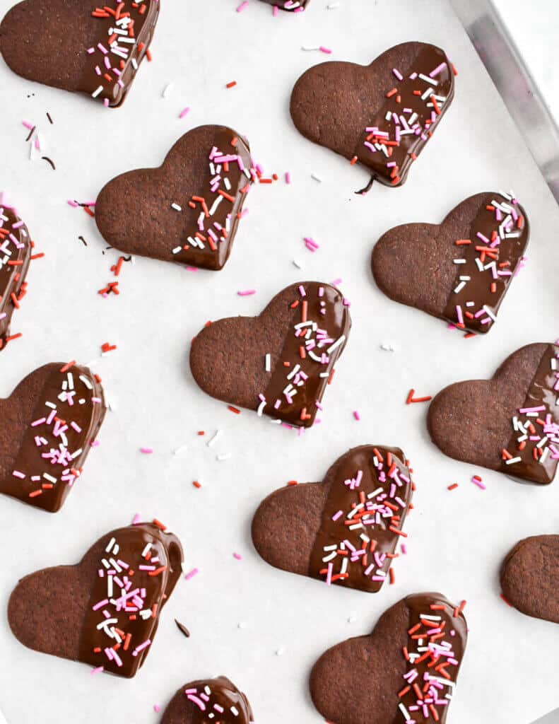 Chocolate heart cutout cookies with sprinkle decorations.