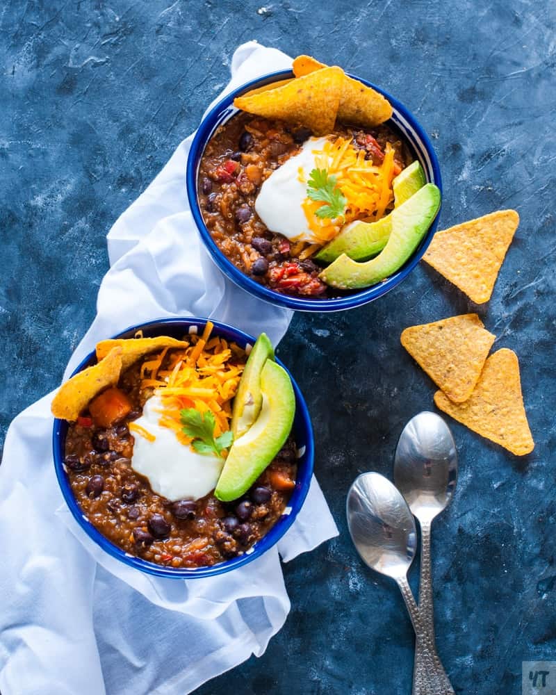 Two bowls of vegan chilli on a blue table.
