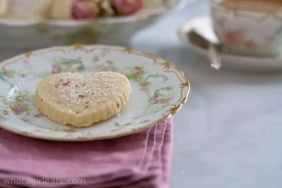 A rose flavored heart cookie in a floral plate.