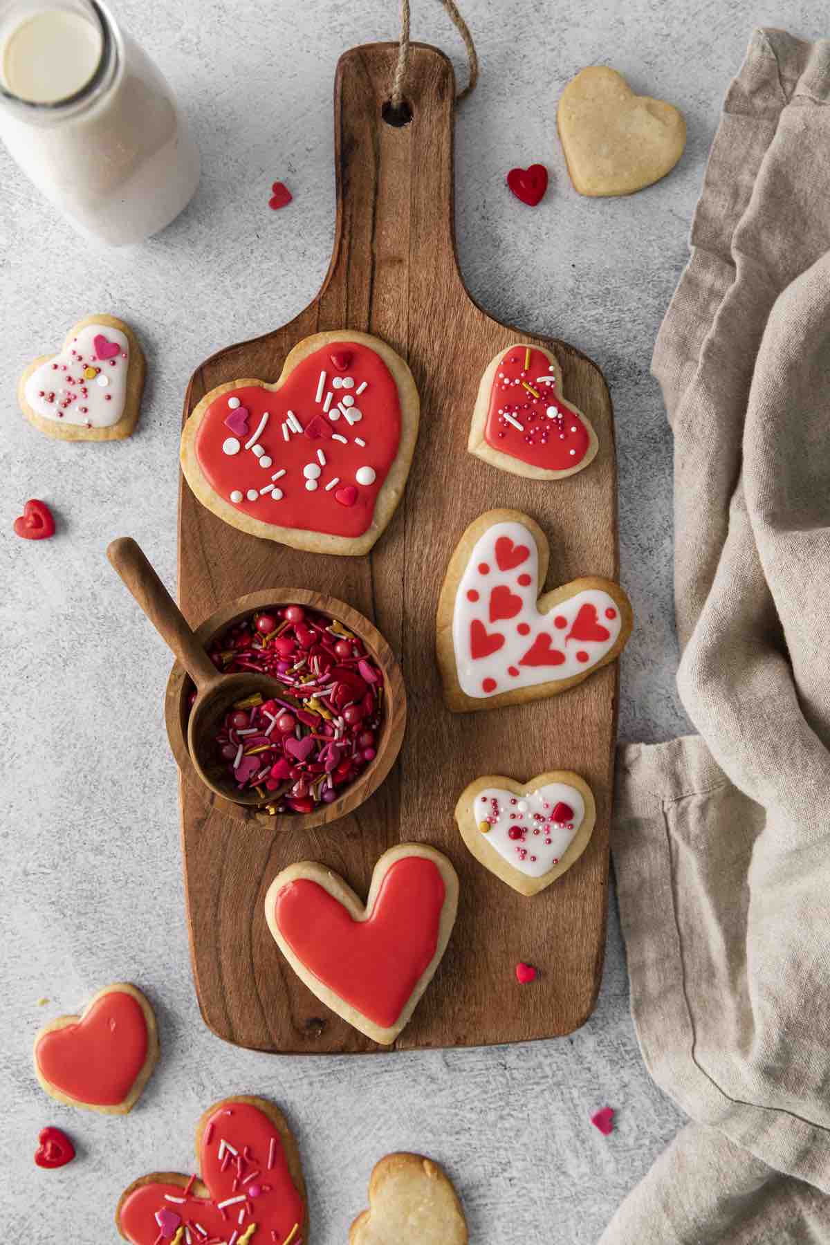Iced shortbread heart cookies on a wooden board.