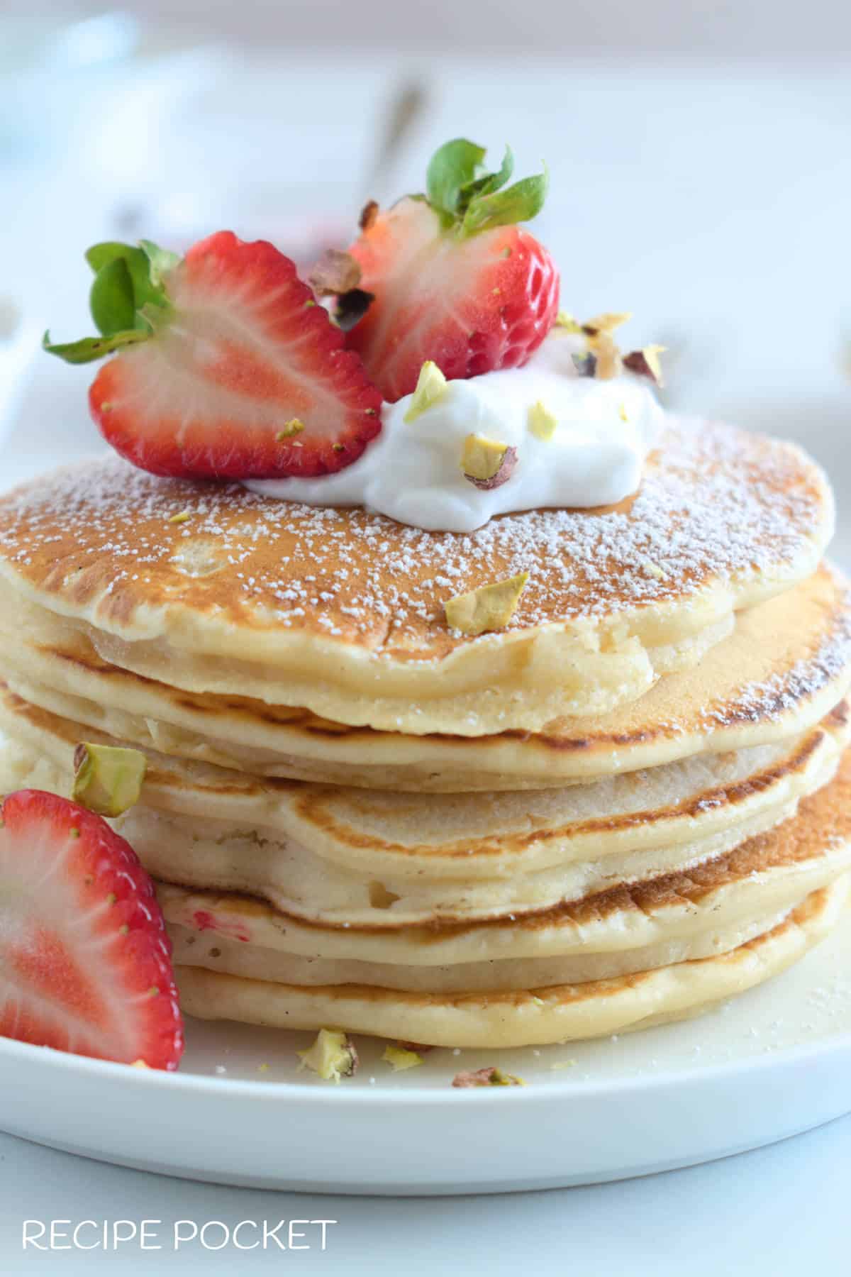 Pancakes with strawberries and cream on top.